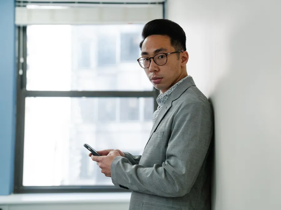 Man checking his phone by an office window