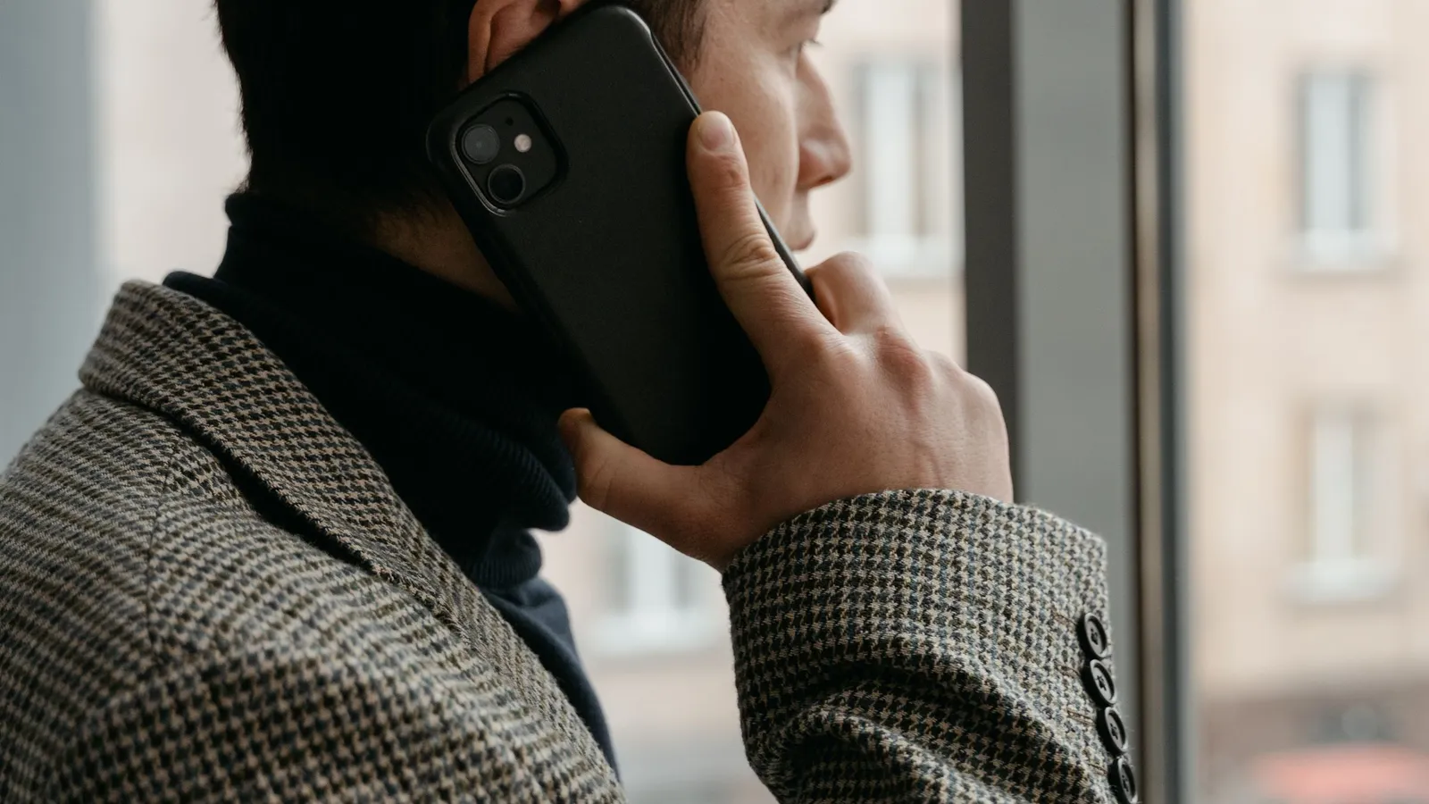 A man on a phone call, looking out a window