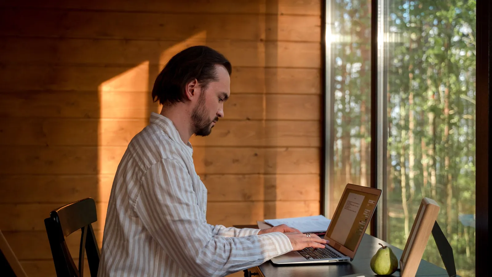 A creator working at a laptop by a window